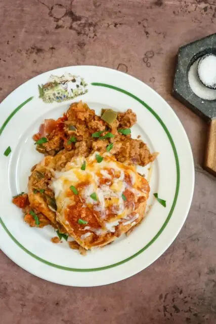 A plate with a serving of beef and biscuit bake with garnish.