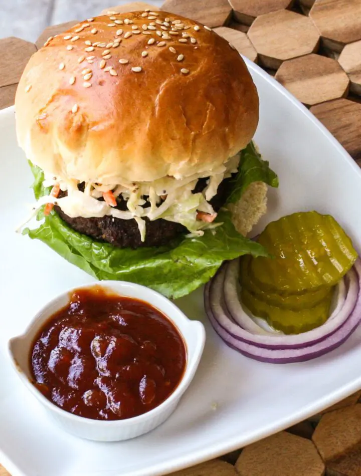 texas burger on a plate with coleslaw topping and bbq sauce