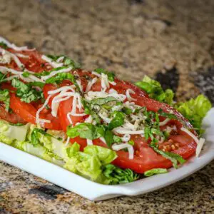 fresh sliced tomatoes on a bed of lettuce with vinaigrette