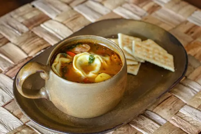 tortellini soup in a cup with crackers