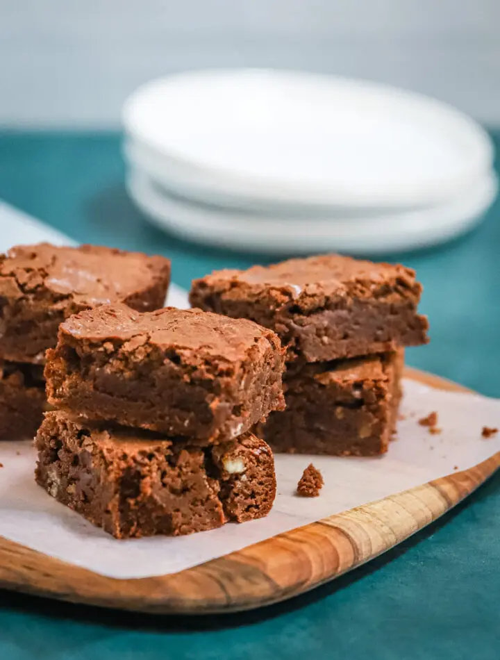 Ultimate fudgy brownies on a parchment paper and teak board, ready to enjoy.