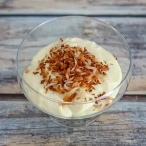 homemade vanilla pudding in a glass dessert dish with toasted coconut