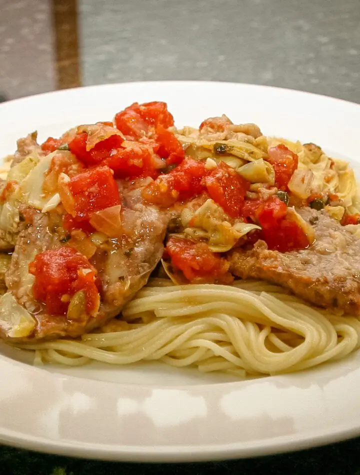 veal cutlets with tomatoes and artichokes on pasta