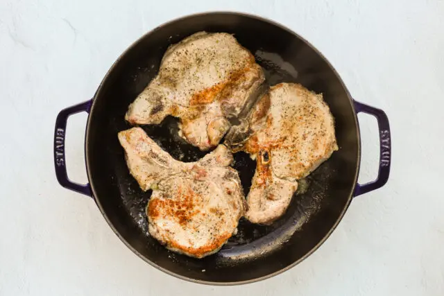 Searing the pork chops in a large skillet or sauté pan.