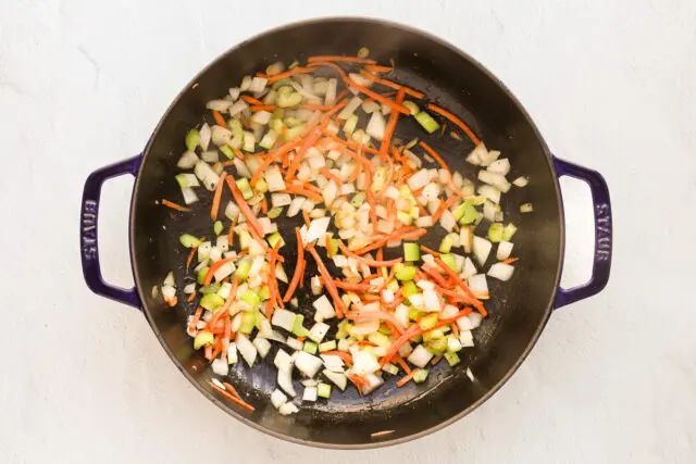 Sautéing the vegetables in a large skillet or sauté pan.