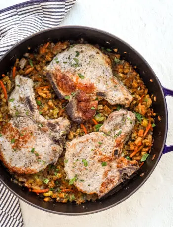 A large Staub saute pan with seasoned stuffing and pork chops baked in the oven.