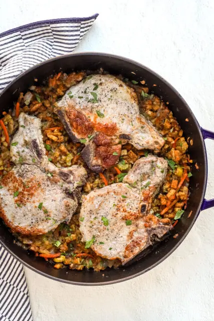 A large Staub saute pan with seasoned stuffing and pork chops baked in the oven.