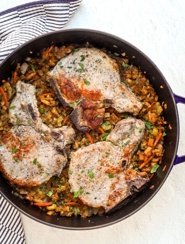 A large Staub saute pan with seasoned stuffing and pork chops baked in the oven.