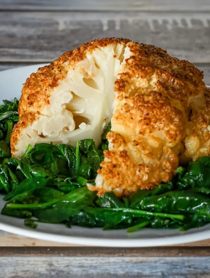 whole roasted cauliflower sliced, on a plate