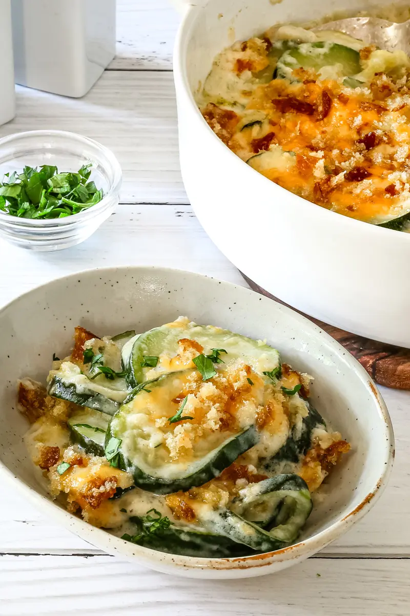 Zucchini casserole on a plate with the baking dish in the