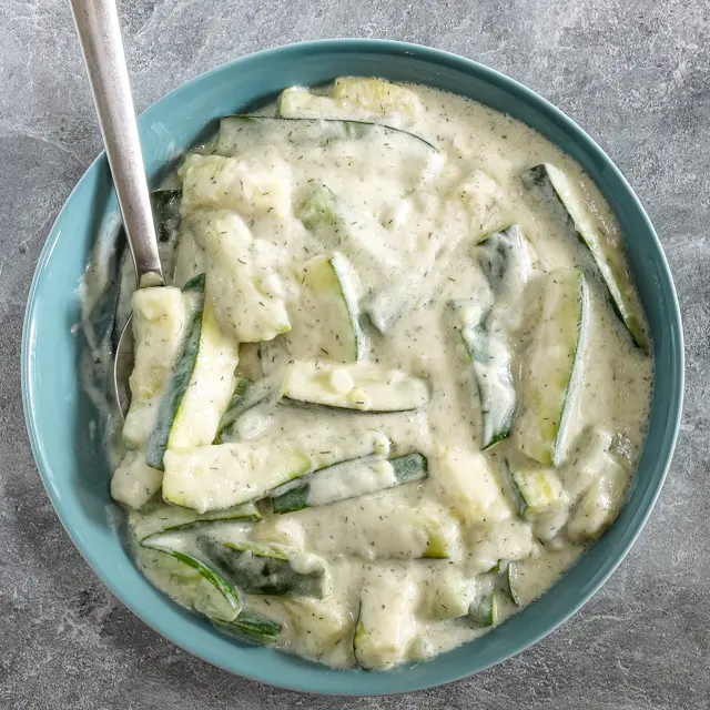 A serving bowl with zucchini cooked in a sour cream sauce.