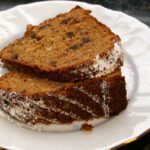 applesauce cake with dates on a plate, topped with powdered sugar