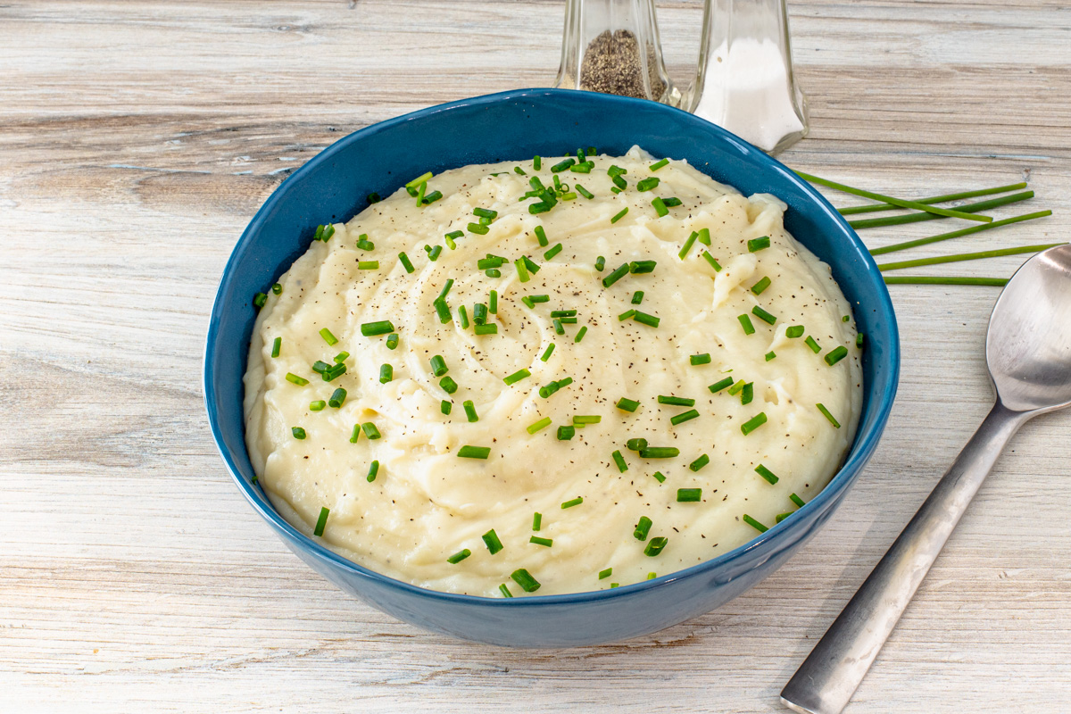A bowl of Instant Pot pressure cooker mashed potatoes with chives for garnish.