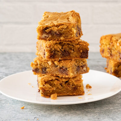 A stack of blondies on a dessert plate with a few more in the background.