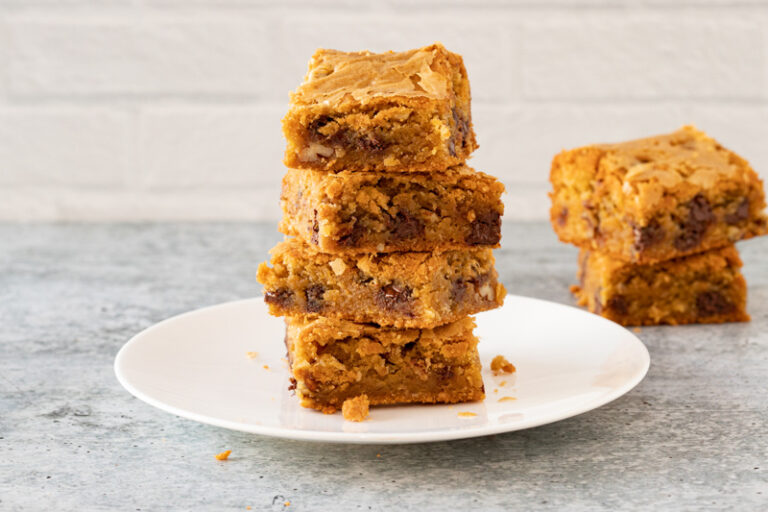 A stack of blondies on a dessert plate with a few more in the background.