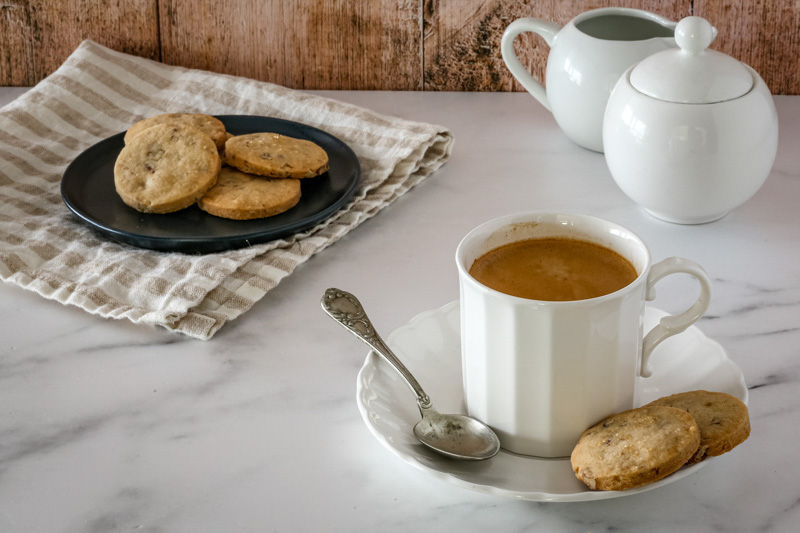 Butter pecan cookies next to a small cup of coffee