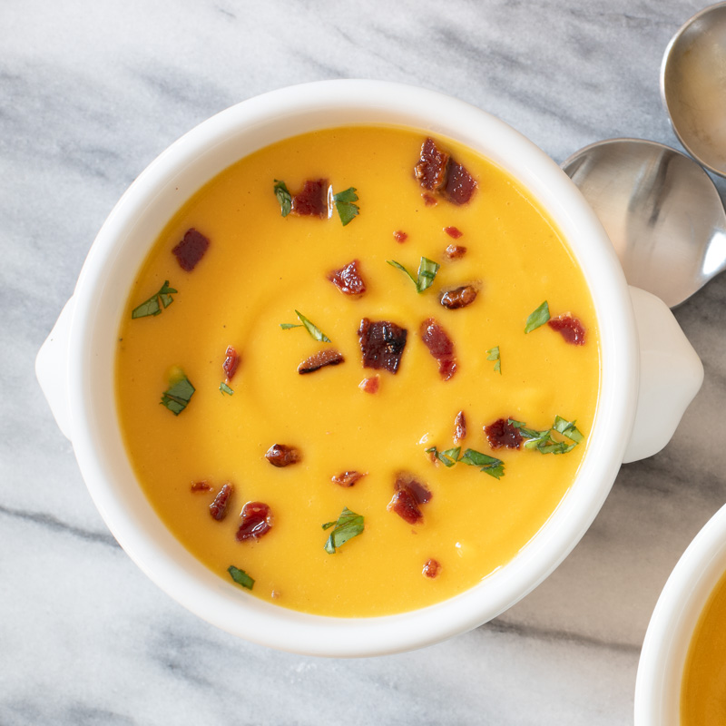 A bowl of butternut squash soup with garnish of bacon.