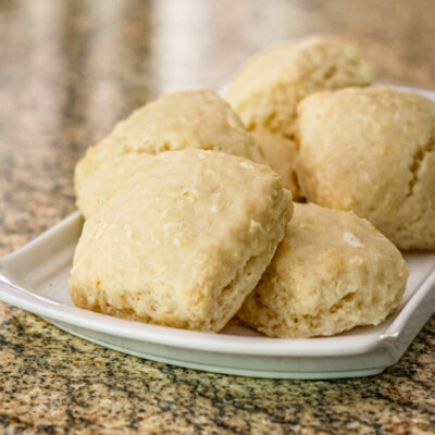Glazed lemon scones on a white tray.