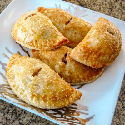 Hand held apple pies on a decorative plate.