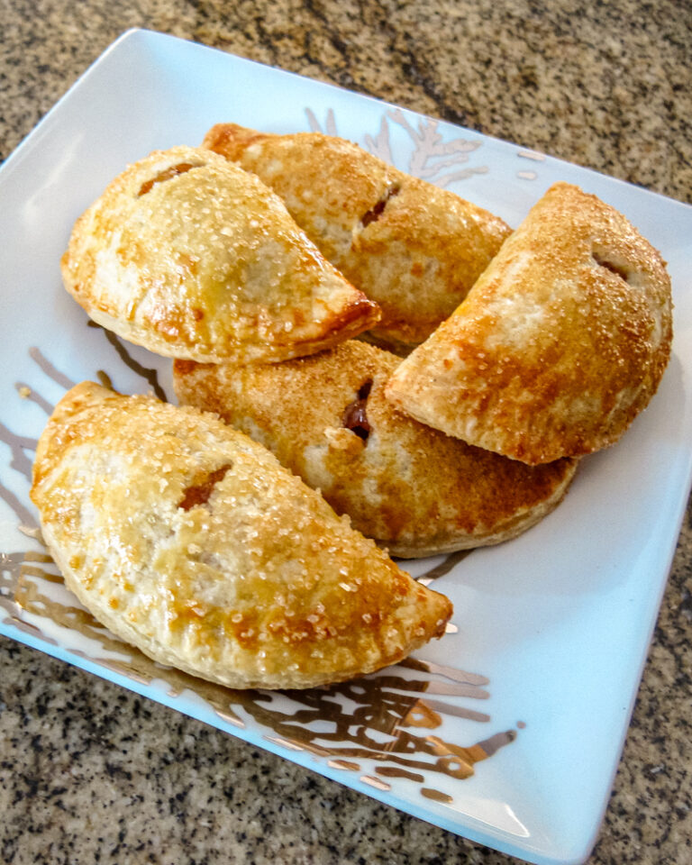 Hand held apple pies on a decorative plate.