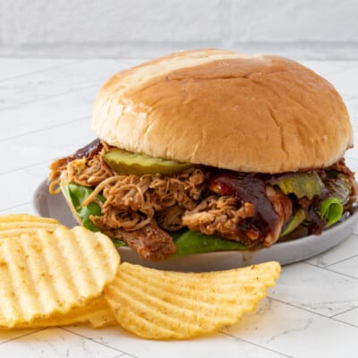 Slow-cooked pulled chicken sandwich with barbecue sauce and pickles.