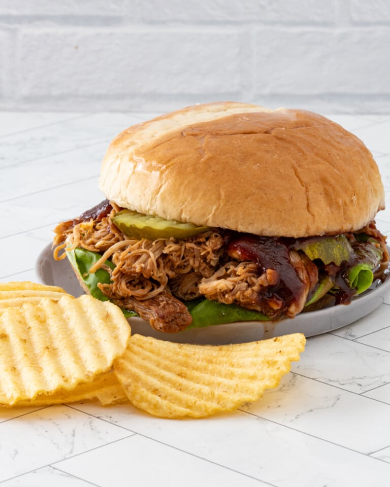 Slow-cooked pulled chicken sandwich with barbecue sauce and pickles.