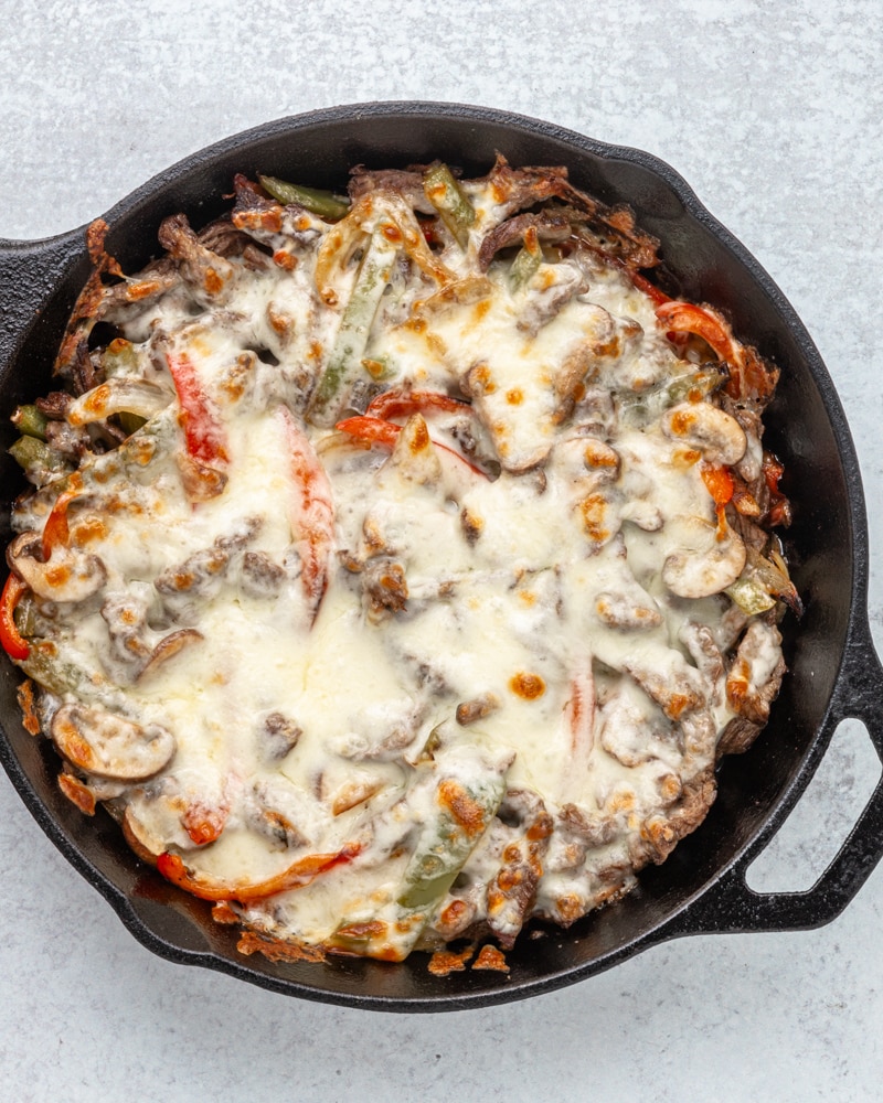 Philly cheesesteak cooked in the skillet with melted cheese topping.