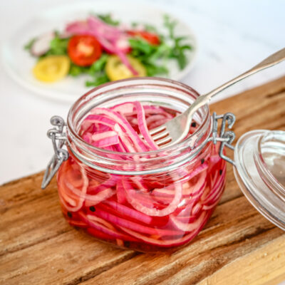 quick pickled onions in a canning jar with a salad in the background