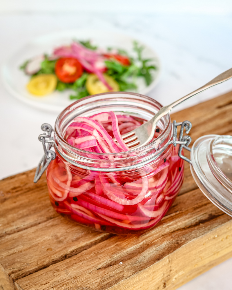 quick pickled onions in a canning jar with a salad in the background