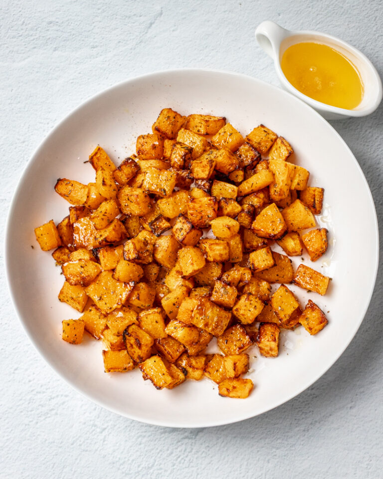 A platter of glazed roasted butternut squash with a small jug of melted butter.