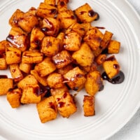 A plate with butternut squash, roasted and drizzled with a balsamic reduction glaze.