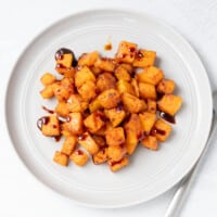 A plate with butternut squash, roasted and drizzled with a balsamic reduction glaze.