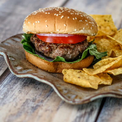 bacon and cheese stuffed burgers on a plate with chips on the side