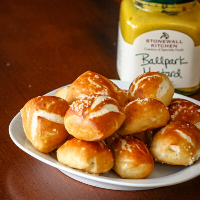 Homemade pretzel bites with mustard in the background.