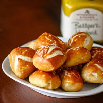 Homemade pretzel bites with mustard in the background.