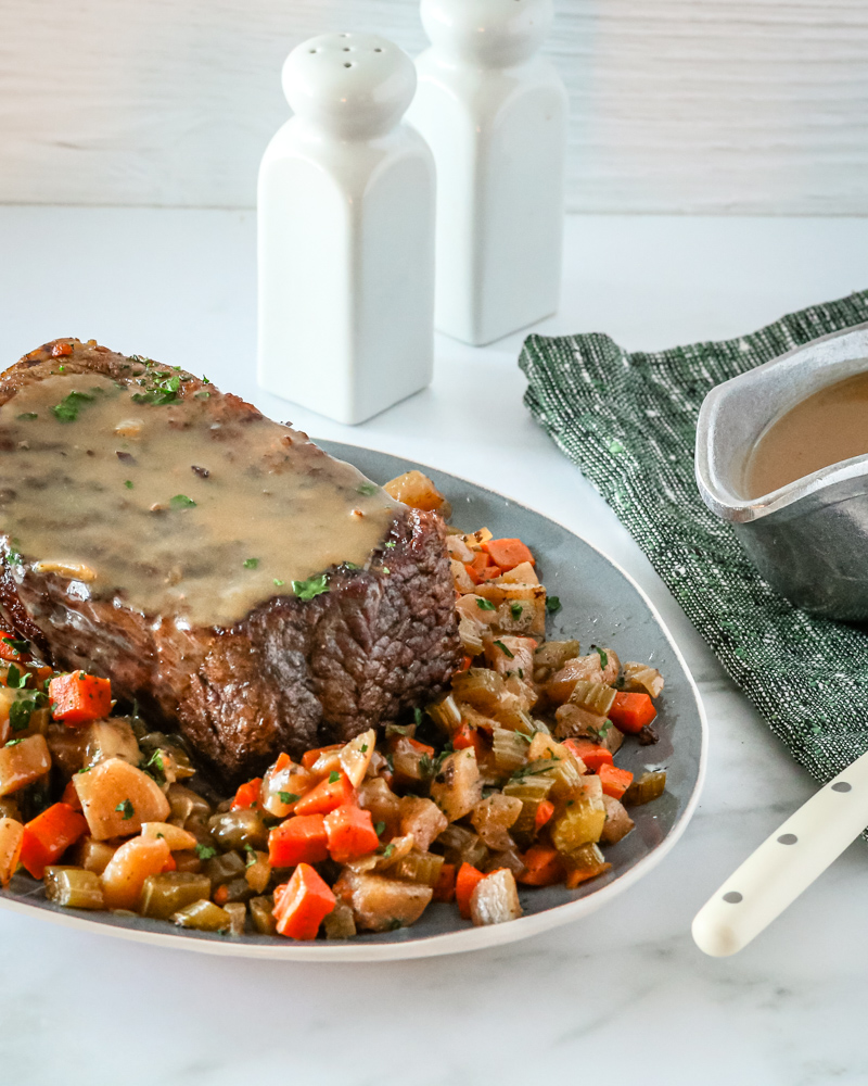 slow cooker pot roast and gravy surrounded by diced vegetables.