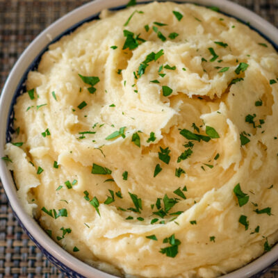 smoked cheddar mashed potatoes garnished with parsley in a serving bowl