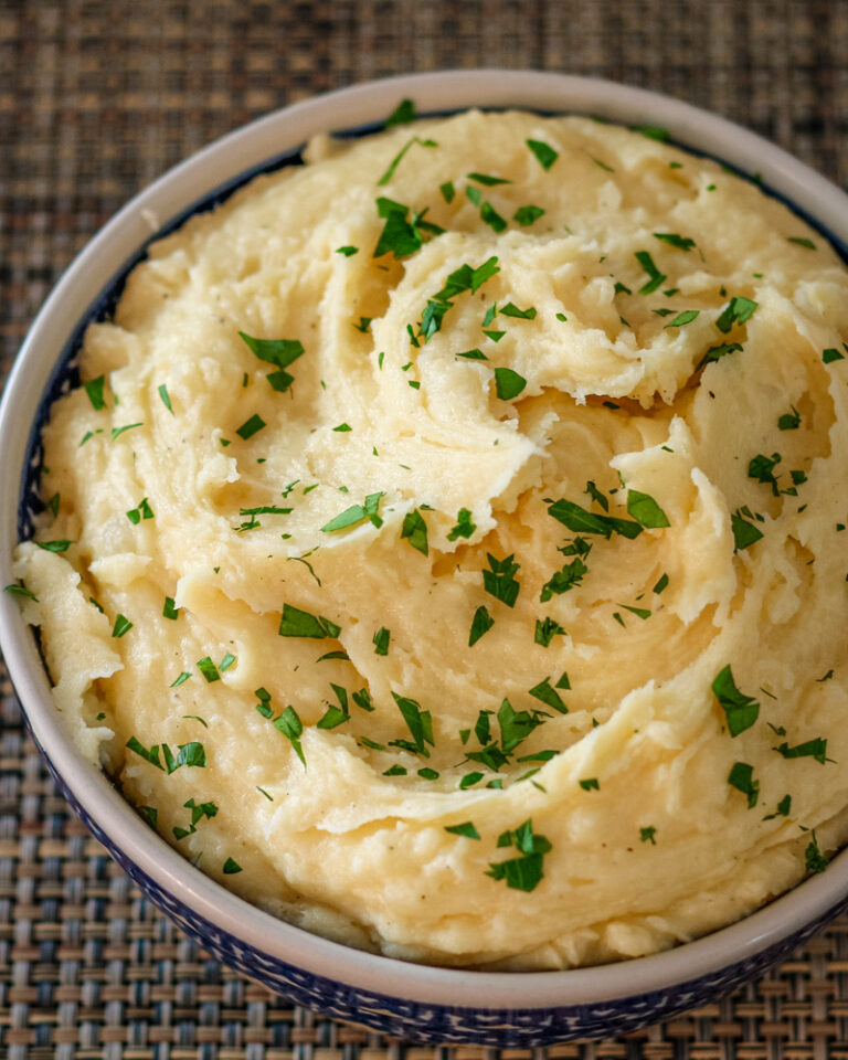 smoked cheddar mashed potatoes garnished with parsley in a serving bowl