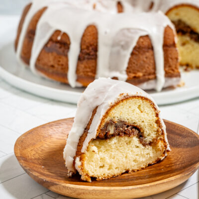 An iced sock-it-to-me cake, sliced, with the rest of the cake in the background.