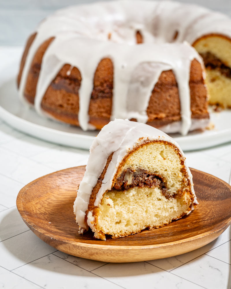 An iced sock-it-to-me cake, sliced, with the rest of the cake in the background.