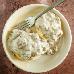 Biscuits and sausage gravy in a small bowl with fork.