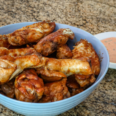 Sriracha glazed chicken wings in a blue bowl.
