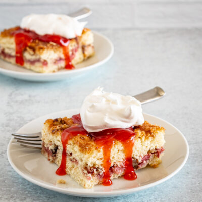 Slices of strawberry crumb cakes on plates with strawberry sauce and whipped cream