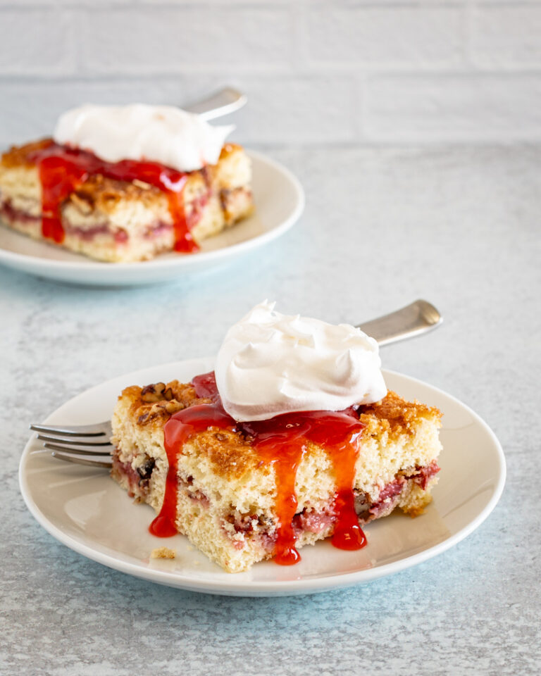 Slices of strawberry crumb cakes on plates with strawberry sauce and whipped cream