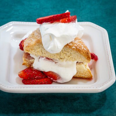 strawberry shortcakes on a plate: cream biscuits with strawberries and whipped cream