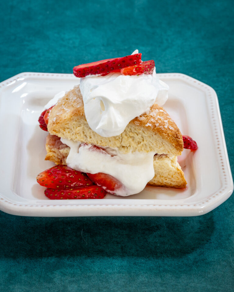 strawberry shortcakes on a plate: cream biscuits with strawberries and whipped cream