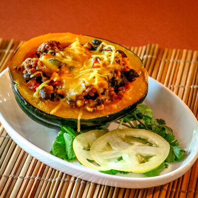 An acorn squash half stuffed with a mixture of Tex-Mex ground beef and beans.