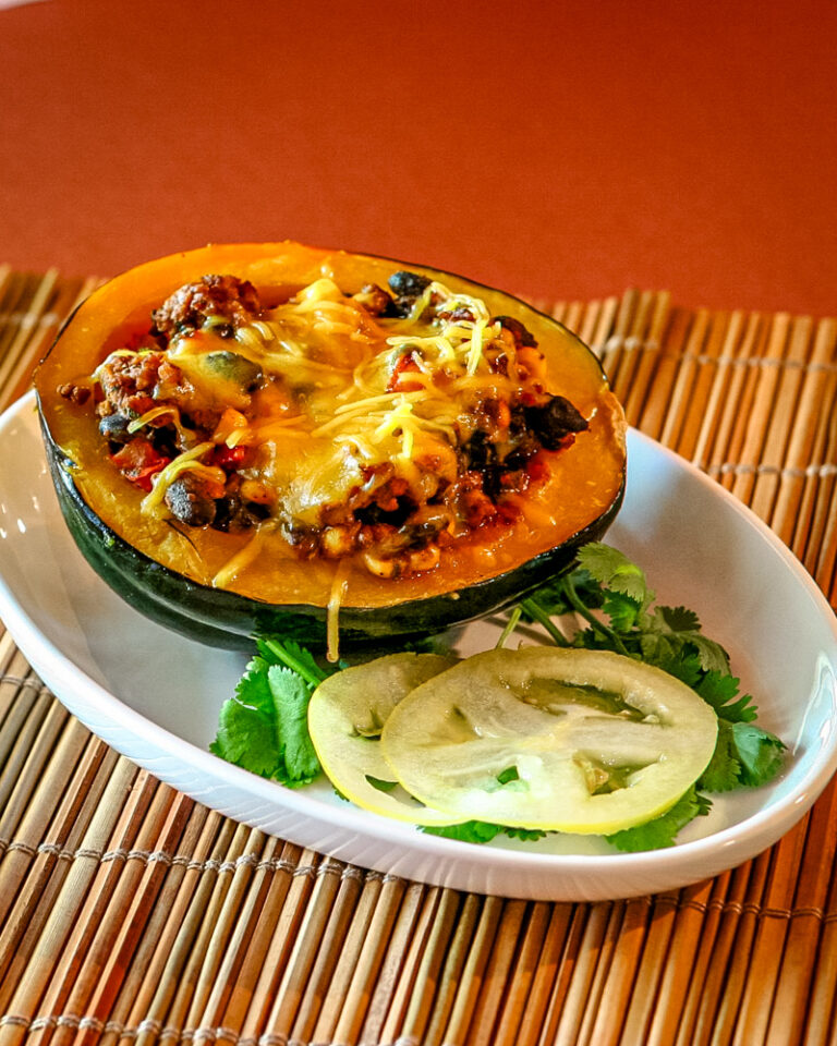 An acorn squash half stuffed with a mixture of Tex-Mex ground beef and beans.