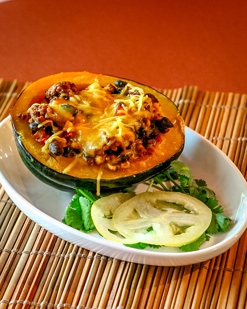 An acorn squash half stuffed with a mixture of Tex-Mex ground beef and beans.