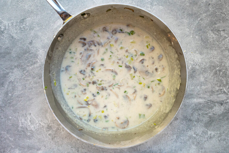 Creamy mushroom and green onion sauce in a skillet.